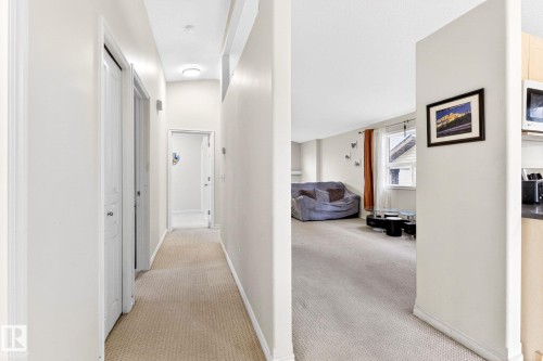 The property features a hallway with carpet flooring and white walls, leading to an open-concept living area with carpet flooring and a window - 20147 48 Avenue, Edmonton, AB - Indoor Photo Showing Other Room