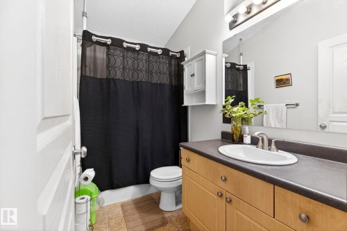 The bathroom features a light wood vanity with a dark countertop and an oval sink - 20147 48 Avenue, Edmonton, AB - Indoor Photo Showing Bathroom