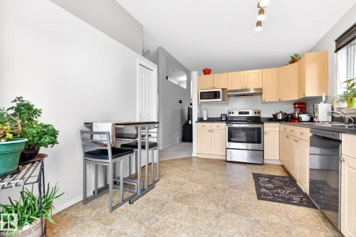 The kitchen features light wood cabinetry, stainless steel appliances, and a tiled floor - 20147 48 Avenue, Edmonton, AB - Indoor Photo Showing Kitchen