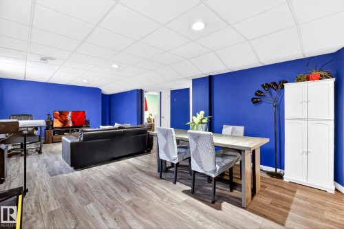 This versatile living area features hardwood flooring, a drop ceiling with recessed lighting, and bright blue walls - 20147 48 Avenue, Edmonton, AB - Indoor Photo Showing Dining Room