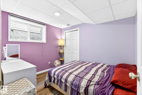 This room features a window with blinds, a bi-fold closet door, and wood-look flooring - 20147 48 Avenue, Edmonton, AB - Indoor Photo Showing Bedroom