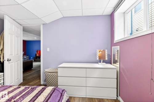 Room featuring two-toned walls, wood-style flooring, a white six-drawer dresser, and a window providing natural light - 20147 48 Avenue, Edmonton, AB - Indoor Photo Showing Bedroom