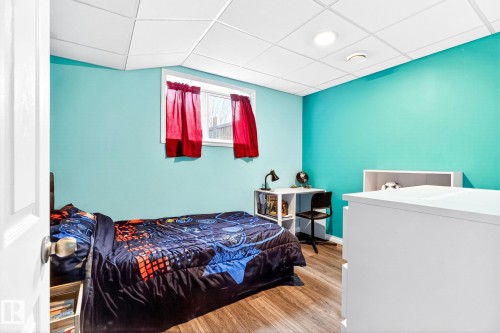 This room features wood-look flooring, a window with red curtains, and a ceiling with recessed lighting - 20147 48 Avenue, Edmonton, AB - Indoor Photo Showing Bedroom