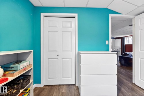 Room featuring a vibrant blue wall, wood-look flooring, and a white bi-fold door - 20147 48 Avenue, Edmonton, AB - Indoor