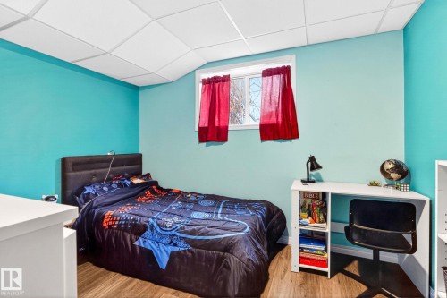 Bedroom with wood-look flooring and a window with red curtains - 20147 48 Avenue, Edmonton, AB - Indoor Photo Showing Bedroom