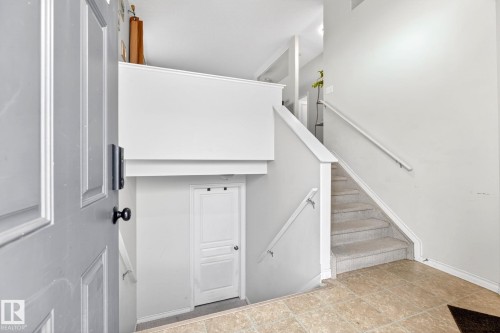 Entryway featuring tile flooring, a staircase with carpeted treads and white handrails, and a white interior door - 20147 48 Avenue, Edmonton, AB - Indoor Photo Showing Other Room
