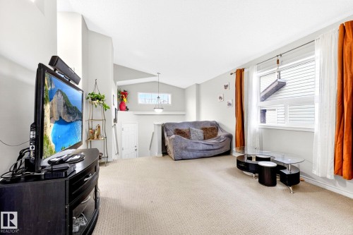 Living area featuring vaulted ceilings, a window with blinds and curtains, and carpeted flooring - 20147 48 Avenue, Edmonton, AB - Indoor