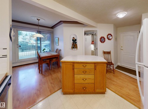 The kitchen features a wooden island with drawers and a light-colored countertop - 31 9914 80 Avenue, Edmonton, AB - Indoor