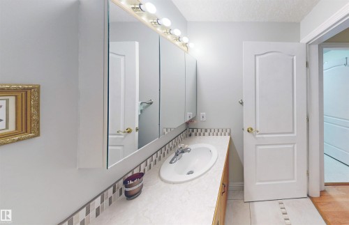 The bathroom features a vanity with an integrated sink, a tiled backsplash, and a large mirror with overhead lighting - 31 9914 80 Avenue, Edmonton, AB - Indoor Photo Showing Bathroom