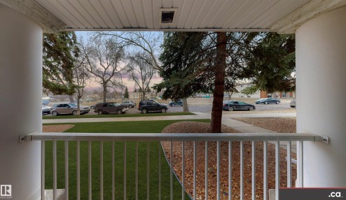 This property features a front-facing balcony with a white railing overlooking a well-maintained lawn - 31 9914 80 Avenue, Edmonton, AB - Outdoor