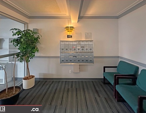 The property features a wall-mounted mailbox system, a contemporary wall sconce, and recessed ceiling details - 31 9914 80 Avenue, Edmonton, AB - Indoor Photo Showing Other Room