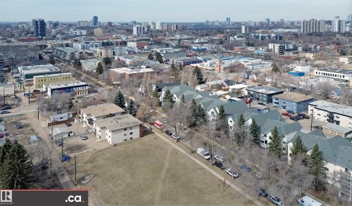 Aerial view of the neighborhood showcasing residential buildings, mature trees, and a distant city skyline - 31 9914 80 Avenue, Edmonton, AB - Outdoor With View