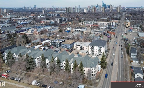 Aerial view showcasing a community with a wide road, various buildings, and a distant city skyline - 31 9914 80 Avenue, Edmonton, AB - Outdoor With View