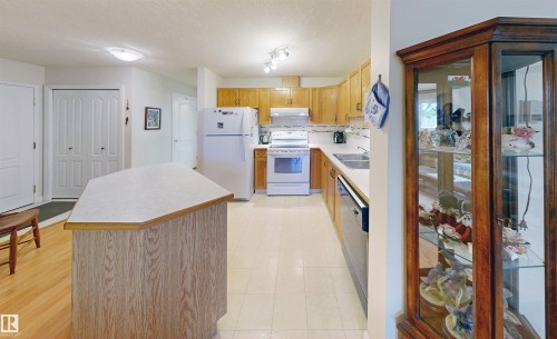 The kitchen features light-toned wooden cabinetry, white appliances, and a central island with a light-colored countertop - 31 9914 80 Avenue, Edmonton, AB - Indoor Photo Showing Kitchen With Double Sink