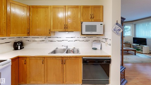 The kitchen features wood cabinetry, a double basin sink, and a microwave - 31 9914 80 Avenue, Edmonton, AB - Indoor Photo Showing Kitchen With Double Sink