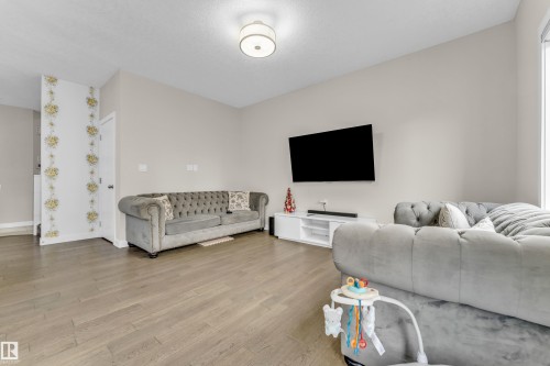 The living area features light-colored walls and wood-look flooring - 32 1703 16 Avenue, Edmonton, AB - Indoor Photo Showing Living Room