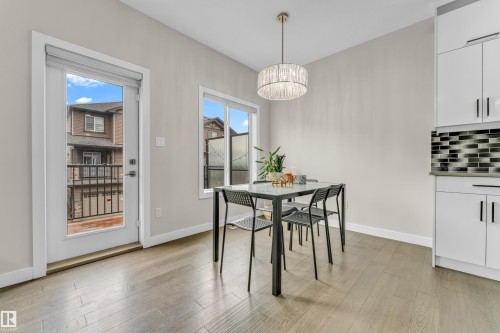 Dining space with hardwood floors, a modern chandelier, and access to an outdoor balcony - 32 1703 16 Avenue, Edmonton, AB - Indoor Photo Showing Dining Room