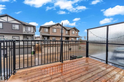 The property features a wooden deck with a black metal railing and a privacy screen - 32 1703 16 Avenue, Edmonton, AB - Outdoor