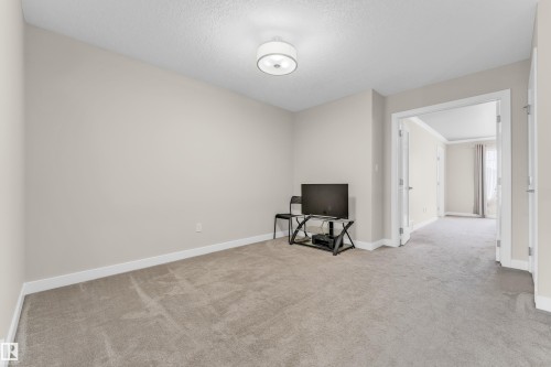 This room features soft gray carpeting, light neutral wall paint, and a modern flush mount light fixture - 32 1703 16 Avenue, Edmonton, AB - Indoor Photo Showing Other Room