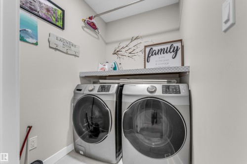 The property includes a dedicated laundry area with two front-loading machines and an overhead shelf - 32 1703 16 Avenue, Edmonton, AB - Indoor Photo Showing Laundry Room