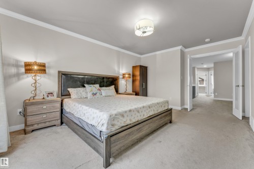 This room features light-colored walls and carpeting, a decorative overhead light fixture, and crown molding - 32 1703 16 Avenue, Edmonton, AB - Indoor Photo Showing Bedroom