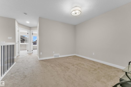 This room features neutral-toned carpet, light-colored walls, and a modern ceiling light fixture - 32 1703 16 Avenue, Edmonton, AB - Indoor Photo Showing Other Room