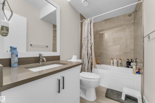 Bathroom featuring a vanity with a rectangular sink and a single-handle faucet, a toilet, and a bathtub with a shower - 32 1703 16 Avenue, Edmonton, AB - Indoor Photo Showing Bathroom