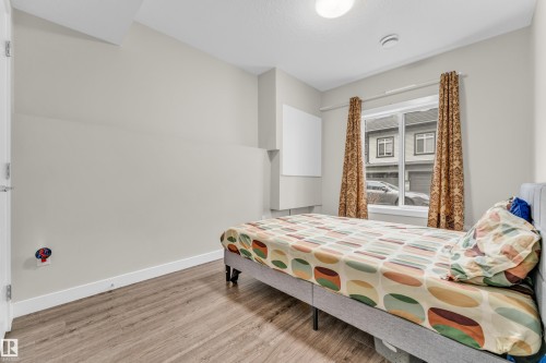 Bedroom with light wood-style flooring and a window with patterned curtains - 32 1703 16 Avenue, Edmonton, AB - Indoor Photo Showing Bedroom