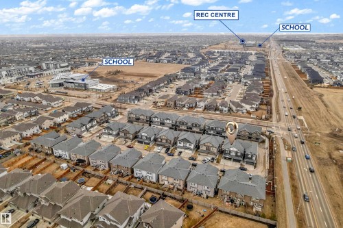 Aerial view of the community, showcasing residential properties, a nearby highway, and local amenities including a school and a recreation center - 32 1703 16 Avenue, Edmonton, AB - Outdoor With View