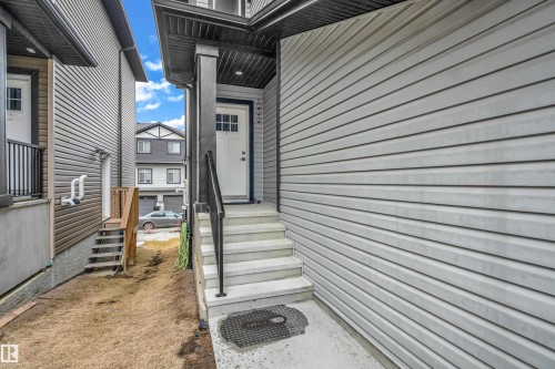 The property features a white door with windows, concrete steps, and a black handrail - 32 1703 16 Avenue, Edmonton, AB - Outdoor With Exterior