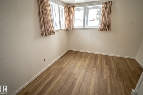 Room featuring light-toned walls, wood-style flooring, and windows with curtains - 5209 49 Ave, St. Paul Town, AB - Indoor Photo Showing Other Room