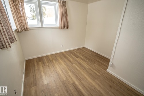 This room features light-colored walls and wood-look flooring - 5209 49 Ave, St. Paul Town, AB - Indoor Photo Showing Other Room