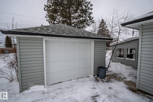 The property includes a single-car garage with a white panel garage door and light grey siding, featuring a shingled roof - 5209 49 Ave, St. Paul Town, AB - Outdoor With Exterior