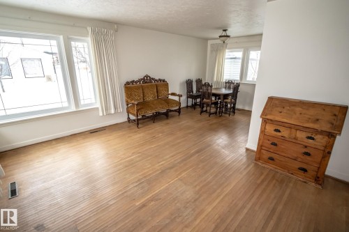This inviting room features light wood flooring, ample natural light from multiple windows, and crisp white walls - 5209 49 Ave, St. Paul Town, AB - Indoor