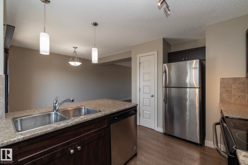 The kitchen features a double stainless steel sink, granite countertops, and stainless steel appliances - 1403 Cunningham Drive, Edmonton, AB - Indoor Photo Showing Kitchen With Double Sink