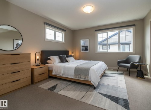 This room features carpeting, neutral-toned walls, and two windows providing natural light - 1403 Cunningham Drive, Edmonton, AB - Indoor Photo Showing Bedroom