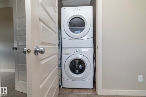 Dedicated laundry space featuring a stacked white washer and dryer unit - 1403 Cunningham Drive, Edmonton, AB - Indoor Photo Showing Laundry Room