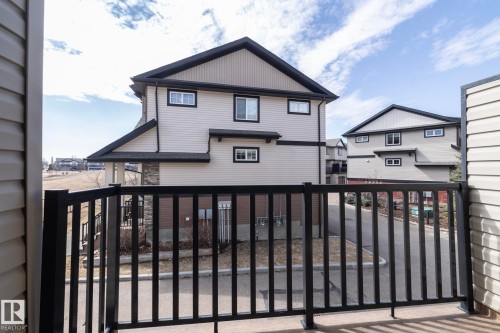Exterior view of the property featuring light-colored siding, black trim, and a black balcony railing - 1403 Cunningham Drive, Edmonton, AB - Outdoor With Exterior