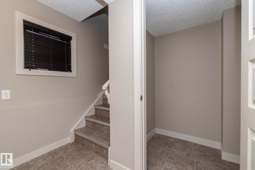 The property features a staircase with carpeted treads and a window with blinds - 1403 Cunningham Drive, Edmonton, AB - Indoor Photo Showing Other Room