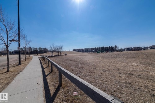 The property is situated within a community featuring a paved walking path, a large open field, and distant residential buildings - 1403 Cunningham Drive, Edmonton, AB - Outdoor With View