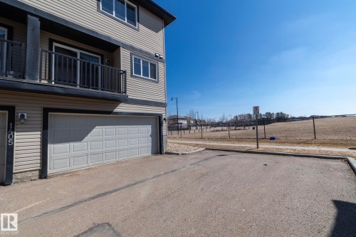 The property features light-colored siding with dark trim, a two-car garage, and a balcony with dark railings - 1403 Cunningham Drive, Edmonton, AB - Outdoor