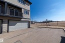The property features light-colored siding with dark trim, a two-car garage, and a balcony with dark railings - 1403 Cunningham Drive, Edmonton, AB  - Outdoor 