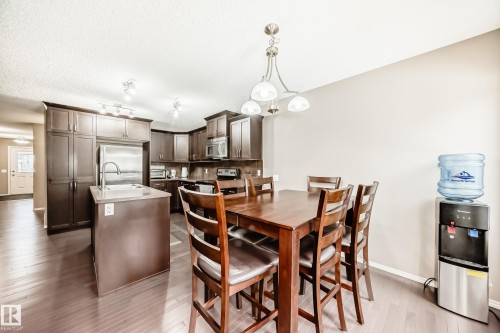Open concept kitchen and dining area featuring dark wood flooring, dark cabinetry, and a kitchen island with a sink - 8 13838 166Ave, Edmonton, AB - Indoor Photo Showing Dining Room