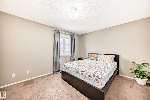 The bedroom features neutral-toned walls, carpeting, and a window with curtains - 8 13838 166Ave, Edmonton, AB - Indoor Photo Showing Bedroom