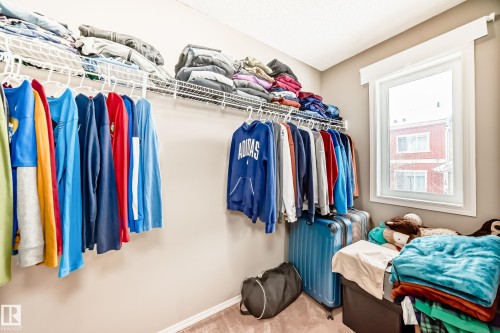 This room features wall-mounted shelving and hanging rods for storage, with a window providing natural light - 8 13838 166Ave, Edmonton, AB - Indoor With Storage