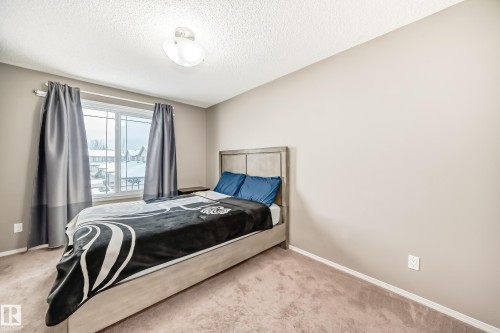 This room features neutral-toned walls, a window with grey curtains, and carpeted flooring - 8 13838 166Ave, Edmonton, AB - Indoor Photo Showing Bedroom