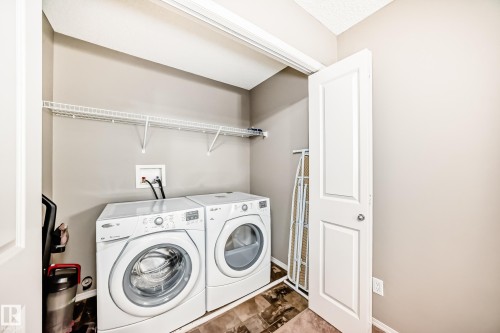 Dedicated laundry area featuring a washer and dryer, a wire shelving unit, and tiled flooring - 8 13838 166Ave, Edmonton, AB - Indoor Photo Showing Laundry Room