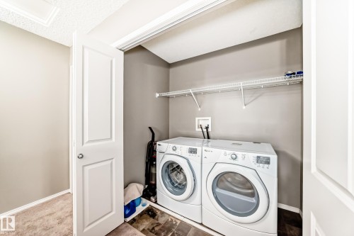 Laundry area featuring a washer and dryer, a wire shelf, and neutral-toned walls - 8 13838 166Ave, Edmonton, AB - Indoor Photo Showing Laundry Room