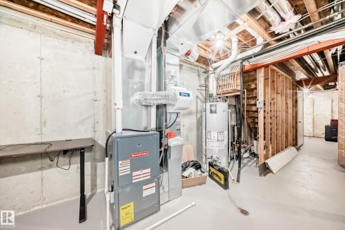The property includes a utility area with exposed concrete walls, a water heater, and a furnace - 8 13838 166Ave, Edmonton, AB - Indoor Photo Showing Basement