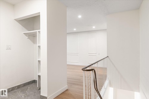 The property features a minimalist interior design with a built-in shelving unit, hardwood flooring, and recessed lighting - 6540 184 Street, Edmonton, AB - Indoor